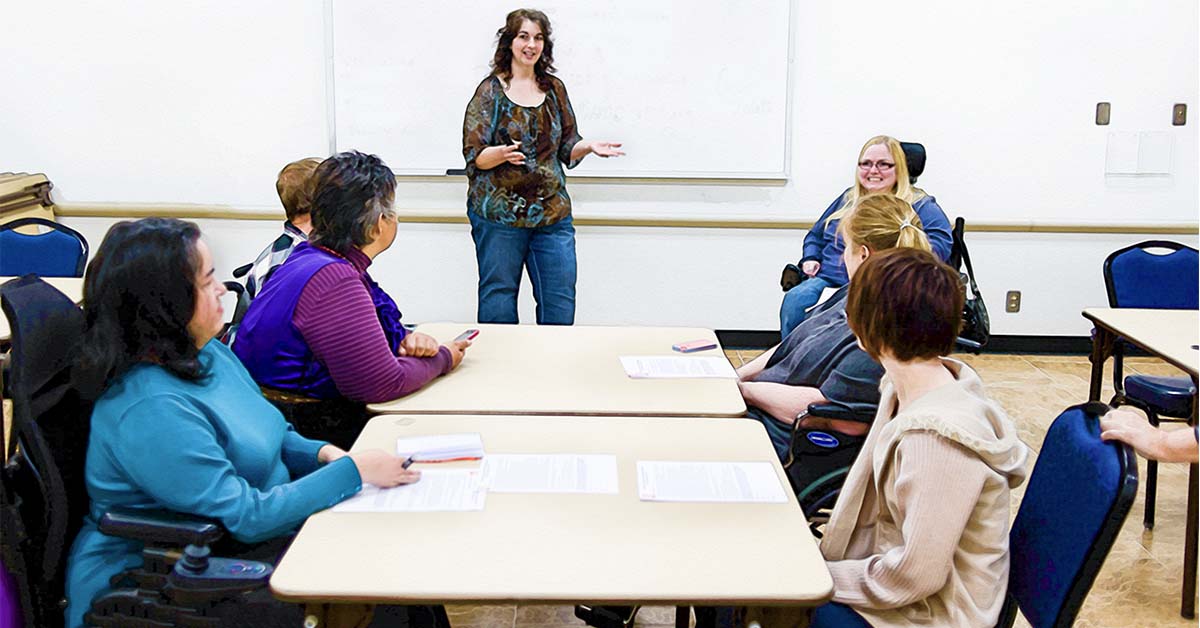 Photograph: Lynn Black teaching a group of people who have disabilites in a classroom.