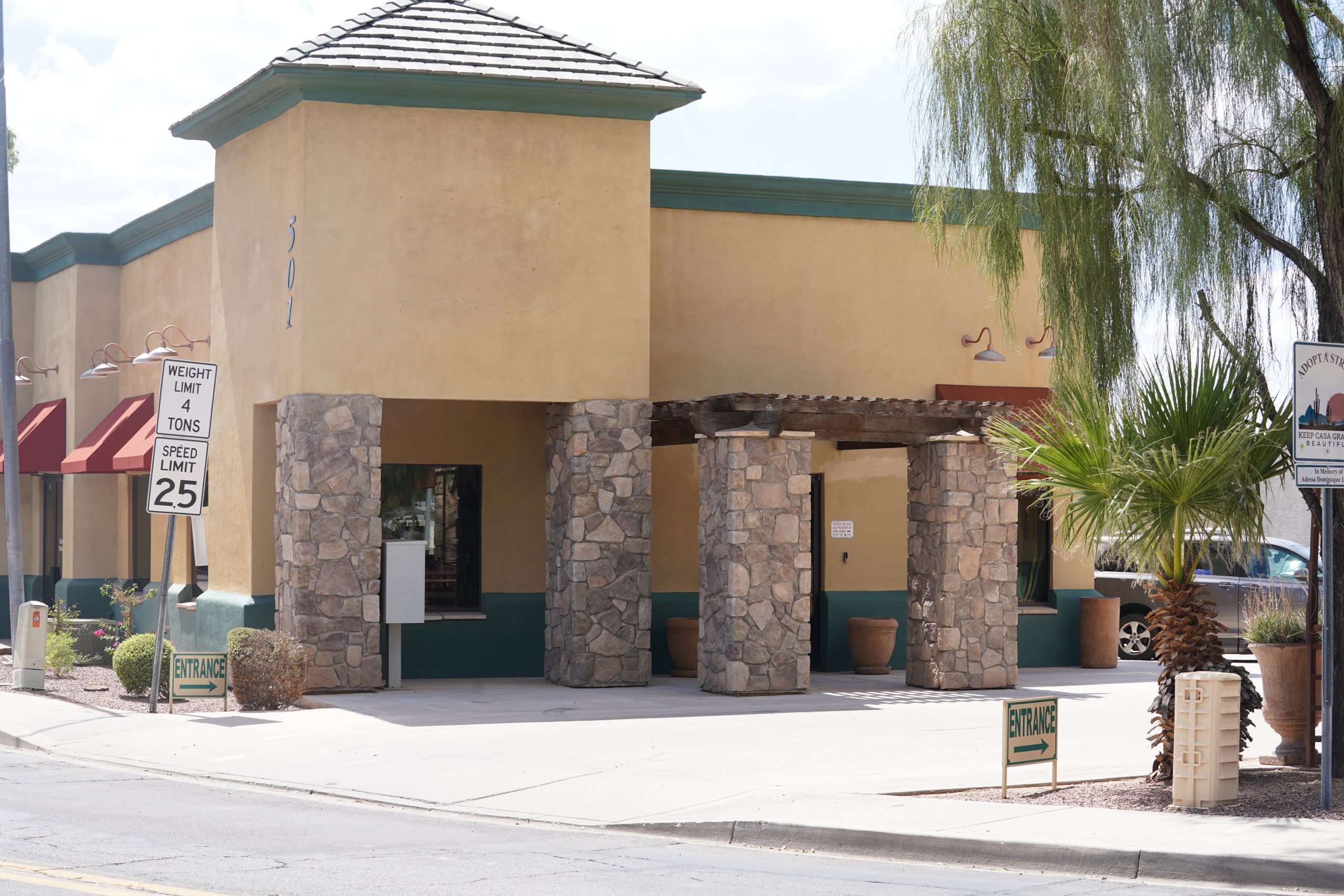 a brown office building entrance on the corner with a entrance sign visible